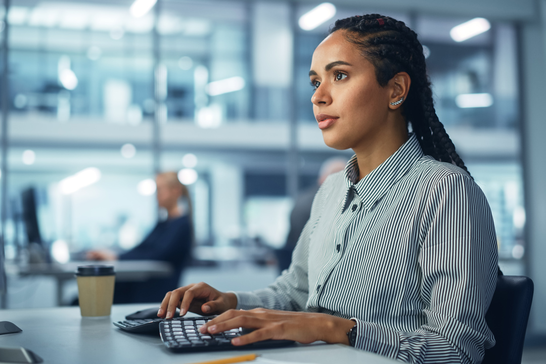 Analyst reviewing project data while working at desktop computer.