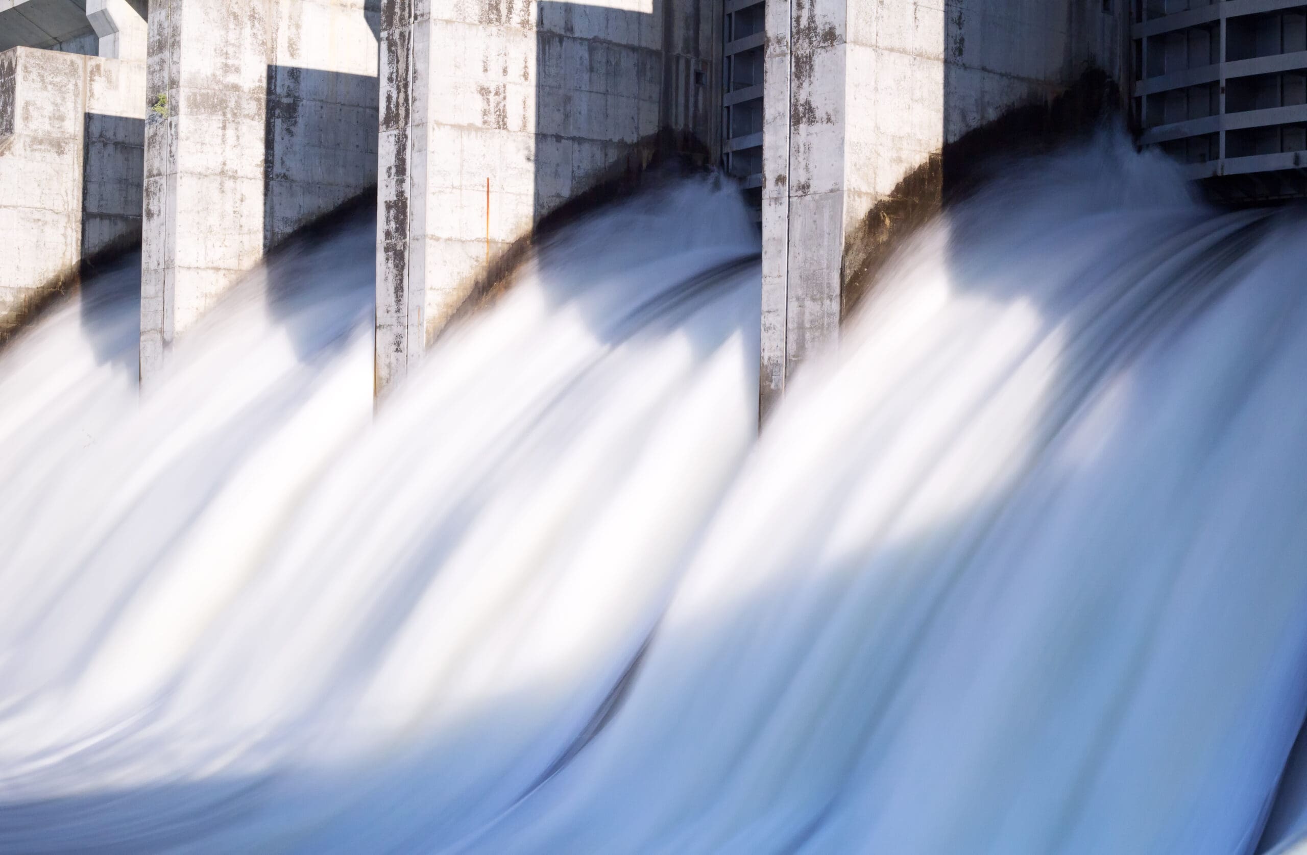 Water rushing out of opened gates of a hydro electric power dam in long exposure Project professional working on contracts for new mega project